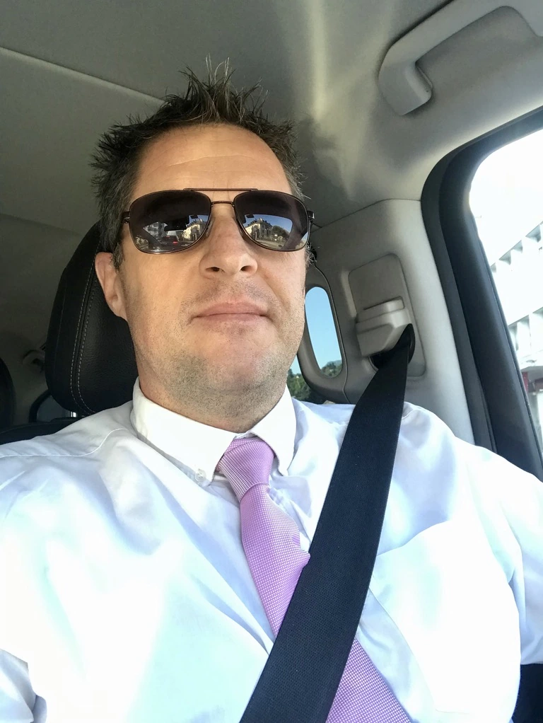 Guillaume Léger Grain, founder of Leocleme Prestige, aboard a vehicle wearing a shirt and tie.