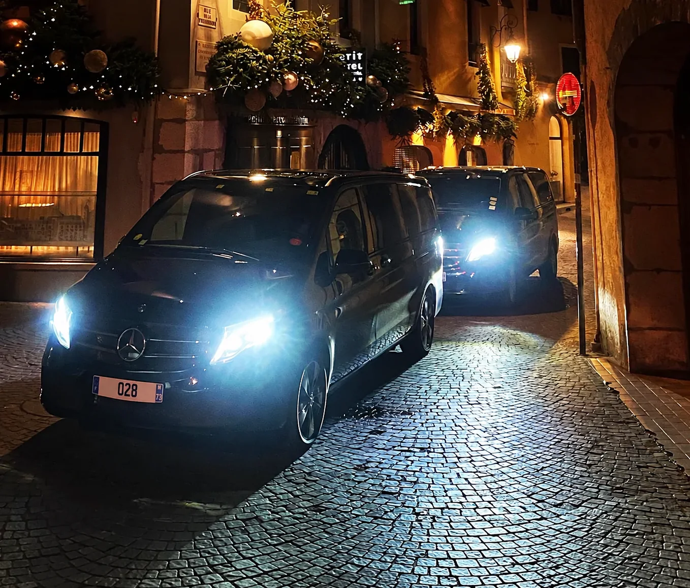 Two Leocleme Prestige Mercedes vans outside Petit Hôtel Confidentiel in Chambéry at night.